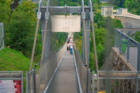People crossing a metal suspension bridge over a green gorge, Rappbodetalsperre, Harz Mountains,