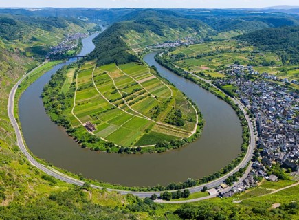 A winding river bend surrounds an agricultural landscape surrounded by hills, with a neighbouring