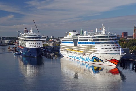 Two large cruise ships in a quiet harbour, with water and city in the background, Aida, Mein