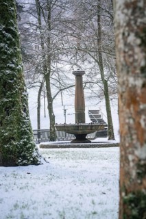 A snow-covered fountain surrounded by peaceful trees in winter, spa garden, Bad Wildbad, Black