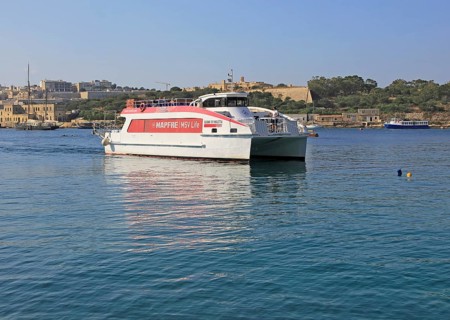 Mapfre Topcat ferry boat crossing harbour from Valletta to Sliema, Malta passing Fort Manoel
