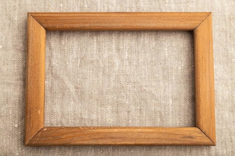 Wooden frame on smooth white linen tissue. Top view, flat lay, natural textile background and