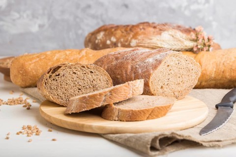 Sliced bread with different kinds of fresh baked bread on a white wooden background. side view,
