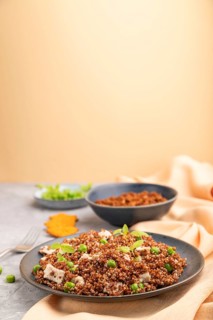 Quinoa porridge with green pea and chicken on ceramic plate on a gray concrete background and