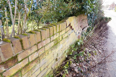 Impact damage to red brick garden wall caused by vehicle reversing, Suffolk, England, UK