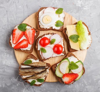 Set of different sandwiches with cheese, radish, lettuce, strawberry, sprats, tomatoes and cucumber