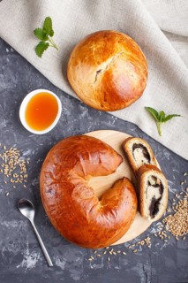 Homemade yeast buns and rolls with poppy seeds and honey on a black concrete background. top view,