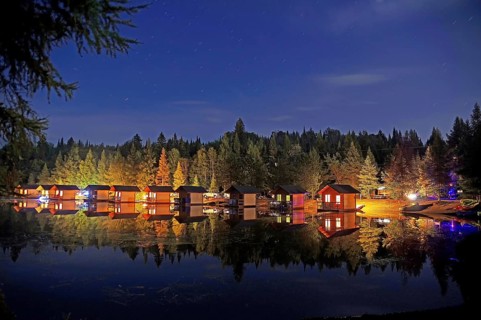 Illuminated little holiday cabins standing by a lake on a campsite, stars, romance, Quebec, Canada,