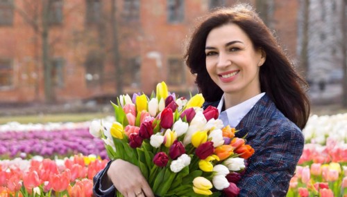A smiling woman with a bouquet of fresh tulips stands in a park, AI generated, AI generated