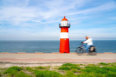 North Sea dyke near Westkapelle, Westkapelle Laag lighthouse, cyclists on the Zeeuwse Wind Route