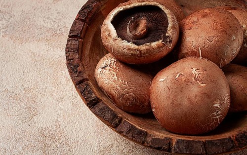 Fresh Portobello mushrooms, in a wooden bowl, top view, close-up, no people