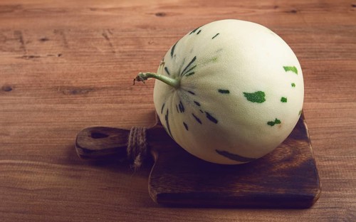 Dino melon, white with green stripes, small size, on the table, close-up, no people