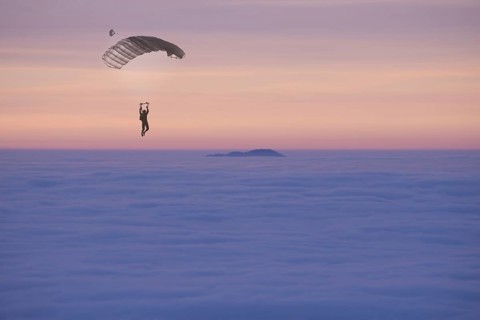 Paraglider Flying over a Cloudscape with a Mountain Peak in Sunset in Ticino, Switzerland, Europe