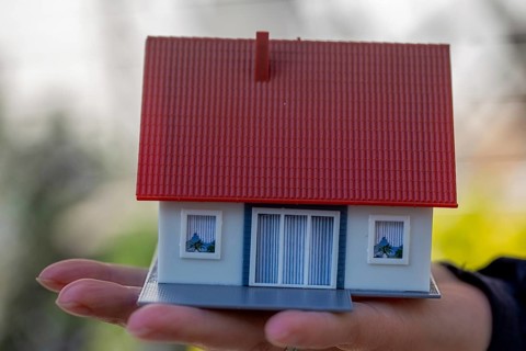 Symbolic image Desire to own a home: woman holding a model house in her hand