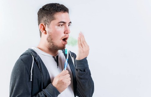 Man holding brush checking bad breath. Person holding brush with bad breath problem
