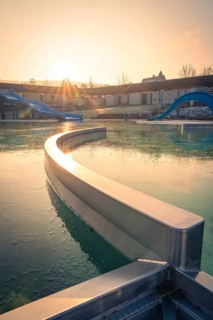 An outdoor pool with a curved water slide, flooded with warm morning sunshine and frozen water,