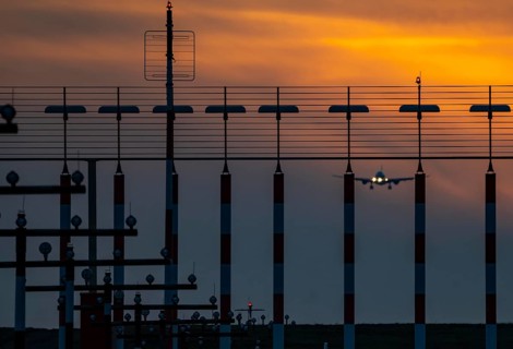 Runway lighting, approach aids, at Düsseldorf International Airport, sunset, aircraft approaching