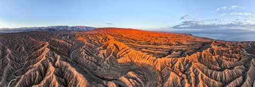 Panorama, landscape of eroded hills at Lake Issyk Kul, badlands at sunrise, mountain peaks of the