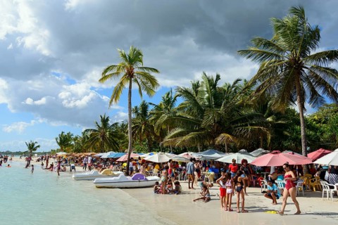 Beachgoers relax under colourful umbrellas next to the calm sea, Boca Chica, Santo Domingo