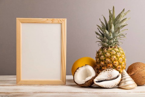 Wooden frame with melon, coconut, pineapple, seashells on gray pastel background. Side view, copy
