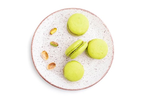 Green macarons or macaroons cakes isolated on white background. Top view, close up
