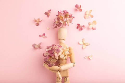 Wooden mannequin holding hydrangea flowers on pink pastel background. copy space, isolated, spring,