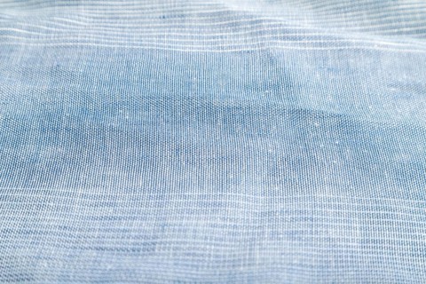Fragment of smooth blue linen tissue. Side view, natural textile background and texture