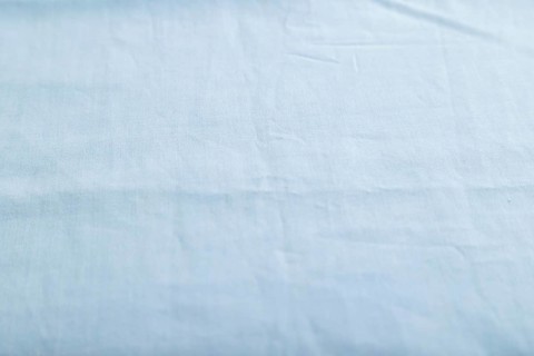 Fragment of smooth cotton blue tissue. Side view, natural textile background and texture