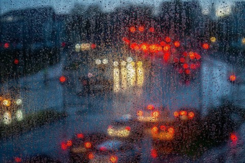 Rainy weather, road traffic, raindrops on a window pane, behind, blurred, lights of vehicles on a