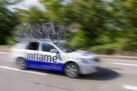 Support vehicle at a cycle race with bicycles on the roof, fast movement emphasised by blurring,