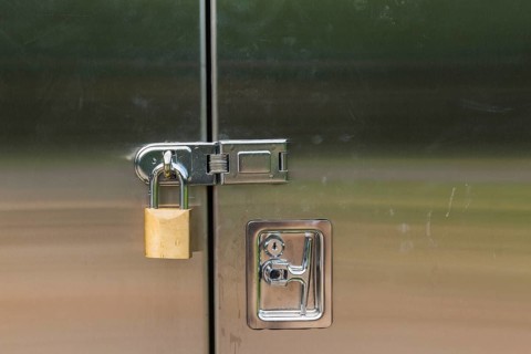 Close-up of stainless steel door on a utility cabinet locked with a brass padlock, Quebec, Canada,