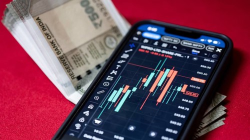 Stock market graph or chart display on a mobile phone against Indian 500 rupee paper currency note