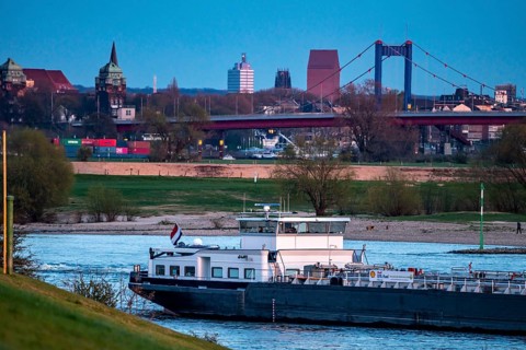 Cargo ship on the Rhine near Duisburg-Beeckerwerth, skyline of the city centre, with town hall,