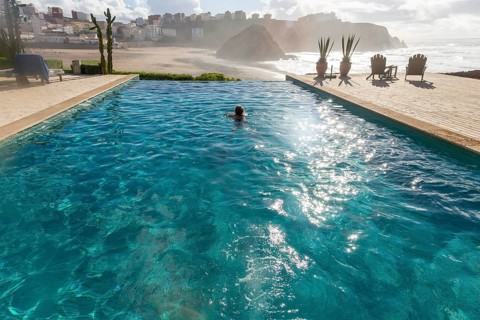 Woman swimming infinity pool by Atlantic Ocean, Hotel auberge Dar Najmat, Mirleft, Morocco, north
