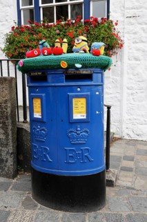 Blue Guernsey Post letterbox with emblem of Queen Elizabeth II in the church square in St Peter