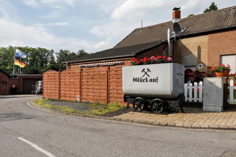 A coal lorry with the miner's greeting Glück auf stands in front of a house in a housing estate in