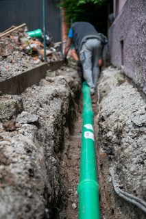 Construction worker, newly laid green sewage pipe, trench, Stuttgart, Baden-Württemberg