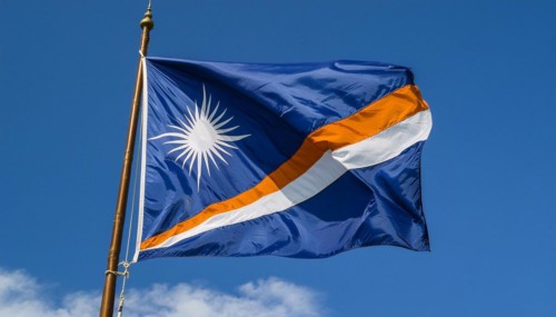 The flag of the Marshall Islands, Pacific Islands, flutters in the wind, isolated against a blue