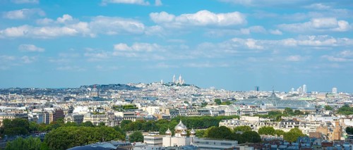 View over the rooftops of Paris on a sunny day in summer with few clouds, white city with some