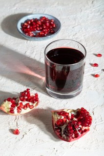 Glass of pomegranate juice on a white concrete background. Hard light, contrast. Side view, close