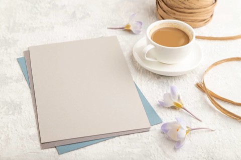Gray paper sheet mockup with spring snowdrop crocus flowers and cup of coffee on gray concrete