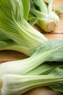 Fresh green bok choy or pac choi chinese cabbage on a brown wooden background. Side view, close up