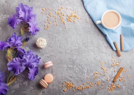 Purple iris flowers and a cup of coffee on a gray concrete background. Morninig, spring, fashion