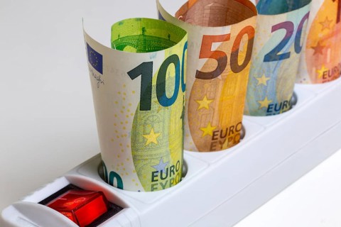 Symbolic image of electricity costs: Multiple socket outlet with banknotes