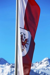 Österreichische Flagge mit schneebeckten Bergen im Hintergrund (Austrian flag with snow-covered
