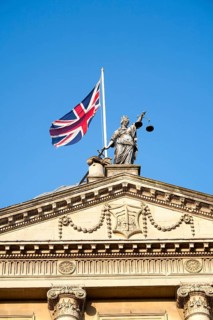Union Jack flag flying with britannia holding scales of Justice on top of the Guildhall building,