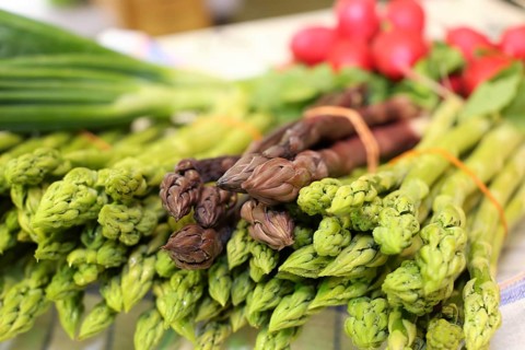 Green and purple asparagus, radishes in the background