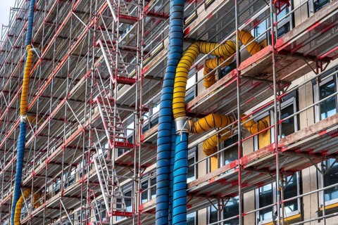 Large construction site, scaffolded shell of an office building complex, air hoses for building