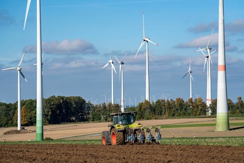 Farmer working in the fields, with a tractor, wind farm above the village of Lichtenau,