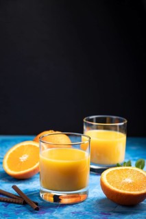 Glass of orange juice on a black and blue background. Hard light, contrast. Side view, copy space